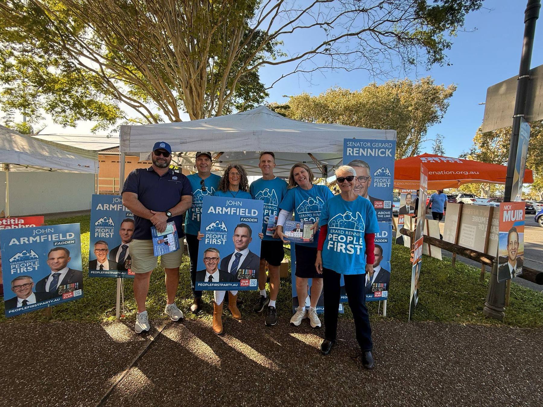 People First volunteers in party t-shirts with John Armfield and Senator Rennick corflutes at a polling booth